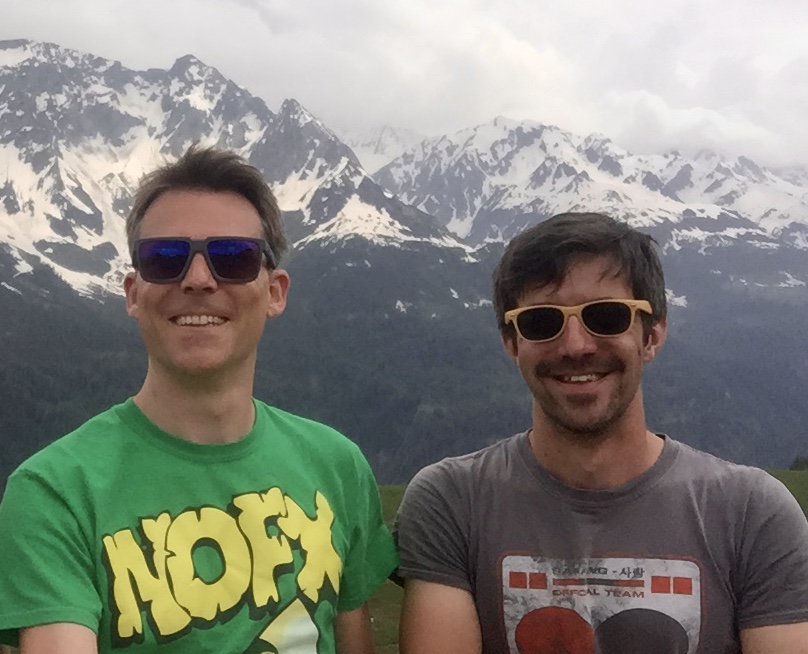 photo of gwil and andrew standing in front of some mountains.