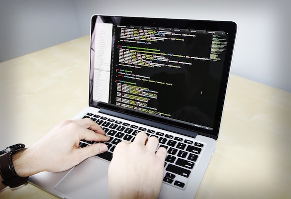 person typing code into a Macbook